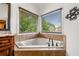 Corner bathtub with tile surround, large windows, and views of the green landscaping at 4235 Night Sky Ln, Cumming, GA 30041