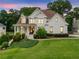 Charming two-story brick home with a landscaped front yard and a welcoming front porch at dusk at 4235 Night Sky Ln, Cumming, GA 30041