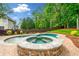 The backyard features a unique pool and spa design, surrounded by a brick patio and mature trees at 4235 Night Sky Ln, Cumming, GA 30041