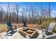 Outdoor brick firepit with chairs is surrounded by beautiful trees, creating a cozy and inviting space for relaxation and entertainment at 6265 Reives Rd, Cumming, GA 30041