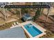 An aerial view of a virtually staged backyard pool with modern design and a pool house surrounded by trees and landscaping at 6265 Reives Rd, Cumming, GA 30041
