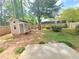 Backyard with a small shed and a concrete patio area, surrounded by a wooden fence and green trees at 5229 Mountain Village Ct, Stone Mountain, GA 30083