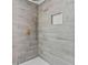 Updated shower with gray wood-look tile surround, hexagon tile niche and floor, plus gold fixtures at 2023 Stoneleigh Dr, Stone Mountain, GA 30087