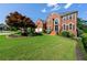 Expansive front lawn of a brick home featuring mature trees and landscaped garden beds at 2436 Camden Lake Nw Vw, Acworth, GA 30101