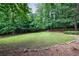 Lush backyard surrounded by mature trees and bordered with stone edging at 10565 Shallowford Rd, Roswell, GA 30075