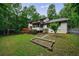Lush backyard featuring a deck, play area, lush landscaping, and a wooded perimeter at 10565 Shallowford Rd, Roswell, GA 30075
