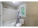 Clean and well-maintained bathroom featuring a shower/tub combo, white tiling and a window for natural light at 10565 Shallowford Rd, Roswell, GA 30075