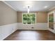 Bright dining room features wood floors, a large window, and white wainscoting for an elegant and inviting space at 10565 Shallowford Rd, Roswell, GA 30075