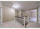 Upstairs hallway featuring carpet and a staircase with white railings and multiple doorways for easy access at 10565 Shallowford Rd, Roswell, GA 30075