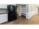 Open kitchen area with black refrigerator, built-in shelving, and hardwood floors at 10565 Shallowford Rd, Roswell, GA 30075