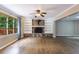 Living room with a stone fireplace, built-in shelving, hardwood floors, and a large window with a view at 10565 Shallowford Rd, Roswell, GA 30075