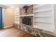 Inviting living room with a stone fireplace, built-in shelving, and beautiful hardwood floors at 10565 Shallowford Rd, Roswell, GA 30075
