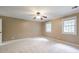 Bright main bedroom featuring plush carpet, a ceiling fan, and two windows offering ample natural light at 10565 Shallowford Rd, Roswell, GA 30075