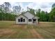 Rear exterior of a white home with black roof, covered porch, and large, flat backyard at 150 Doris Path, Dallas, GA 30157