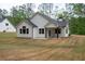 Rear exterior of a home with white siding, black roof, covered porch, and spacious backyard at 150 Doris Path, Dallas, GA 30157