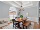 Elegant dining room with tray ceiling, hardwood floors, stylish chandelier, and large window at 4825 Brighton Lake Dr, Cumming, GA 30040