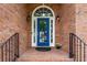 A classic blue front door framed by a brick facade, decorative lights, and wrought iron railings at 4825 Brighton Lake Dr, Cumming, GA 30040
