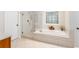 Bright bathroom features a glass enclosed shower and a soaking tub below a decorative window at 3157 Sawyer Ne Ct, Marietta, GA 30066