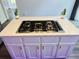 Kitchen island features a built-in gas stovetop and white cabinets at 3748 Woodrose Ct, Snellville, GA 30039