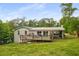 Expansive backyard view featuring a deck, covered patio, lush lawn, and mature trees for privacy at 299 Stockwood Dr, Woodstock, GA 30188