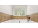 A bathtub under a bright window with tile surround at 3567 Sycamore Bnd, Decatur, GA 30034
