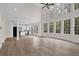 Open living room with hardwood floors, tall windows, and a glimpse of the kitchen, seamlessly blending spaces at 2111 Fernbank Way, Dacula, GA 30019