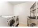 Bright laundry room with modern washer and dryer, stainless steel sink, and open shelving at 50 Dartmouth Ave, Avondale Estates, GA 30002
