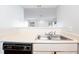 Galley-style kitchen sink with a view of the living room, white cabinets, and black dishwasher at 414 Ridge Creek Dr, Clarkston, GA 30021