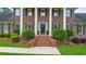 Close-up of a brick home's entrance featuring a brick staircase, a decorative door, and manicured landscaping at 130 Plantation Dr, Stockbridge, GA 30281