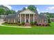 Brick home with stately white columns, black shutters, landscaped yard, and a well-maintained lawn at 130 Plantation Dr, Stockbridge, GA 30281