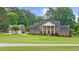 Two-story brick home with mature landscaping, pillars, and a three car detached garage on a well-manicured lawn at 130 Plantation Dr, Stockbridge, GA 30281