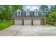 Three-car detached garage with matching brick, dormer windows, and lush green landscaping at 130 Plantation Dr, Stockbridge, GA 30281