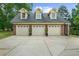 Three-car detached garage with matching brick, dormer windows, and lush green landscaping at 130 Plantation Dr, Stockbridge, GA 30281