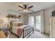 Cozy bedroom features a ceiling fan, a shelf, and a door that leads to a balcony with white curtains at 2112 Ivey Chase Dr, Dacula, GA 30019