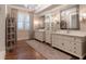 Elegant bathroom featuring dual vanities, decorative mirrors, wood floors, and a central storage tower at 101 Morgan Ln, Canton, GA 30115