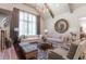 Bright living room features vaulted ceilings, wood beams, two sofas, chairs and a decorative fireplace with brick surround at 101 Morgan Ln, Canton, GA 30115