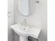 Bathroom with pedestal sink, chrome fixtures, and an oval mirror create a clean and modern aesthetic at 2035 Parkside Ln, Roswell, GA 30076