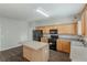 Well-lit kitchen with wood cabinets, black appliances, center island and wood-look flooring at 229 Millwheel Dr, Villa Rica, GA 30180