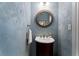 Elegant powder room with stylish vanity, round mirror, and textured blue wall at 601 Ashley Forest Nw Dr, Acworth, GA 30102