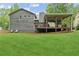 Large backyard and back exterior of home with a deck and wooded views at 1675 Commonwealth Trl, Cumming, GA 30041