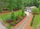 A long driveway leads to a gray home with a two-car garage and lush, green landscaping at 1675 Commonwealth Trl, Cumming, GA 30041