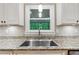 Kitchen with stainless steel sink, granite countertop, white cabinets, and subway tile backsplash at 1675 Commonwealth Trl, Cumming, GA 30041