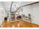 Open living room with wooden beams, stone fireplace, hardwood floors, and neutral walls at 1675 Commonwealth Trl, Cumming, GA 30041