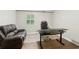 Bright home office features a desk, comfortable office chair, and a brown leather sofa near a window at 1675 Commonwealth Trl, Cumming, GA 30041