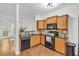 Well-lit kitchen with black appliances, granite countertops and wooden cabinetry and breakfast bar at 3562 Greenwich Ave, Duluth, GA 30096