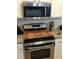 Updated kitchen featuring stainless steel appliances, granite countertops, and a custom stovetop cover at 431 Crested View Dr, Loganville, GA 30052