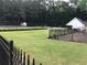 Community tennis court surrounded by lush greenery, a storage shed, and black metal fence at 431 Crested View Dr, Loganville, GA 30052