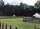 Community tennis court surrounded by lush greenery, a storage shed, and black metal fence at 431 Crested View Dr, Loganville, GA 30052