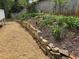 Stone retaining wall next to gravel walkway, mulch flower beds and a wooden fence in the background at 504 Radford Ct, Woodstock, GA 30188