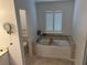 Bright bathroom with a soaking tub with tile surround and window with plantation shutters at 504 Radford Ct, Woodstock, GA 30188